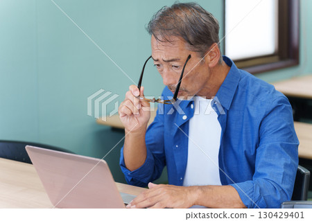 Senior man with presbyopia using a computer 130429401