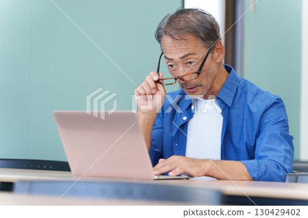 Senior man with presbyopia using a computer 130429402