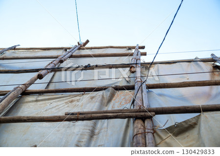 Scaffolding logs secured with wire and covered with a shielding sheet 130429833