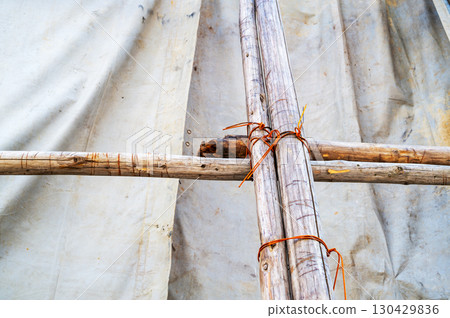 Scaffolding logs secured with wire and covered with a shielding sheet 130429836