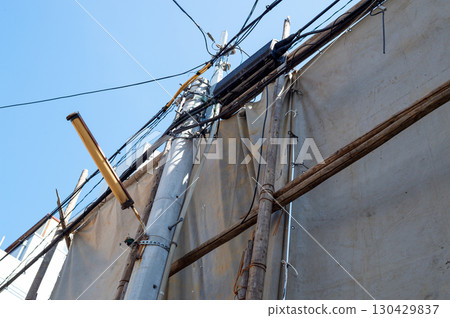 Scaffolding logs secured with wire and covered with a shielding sheet 130429837
