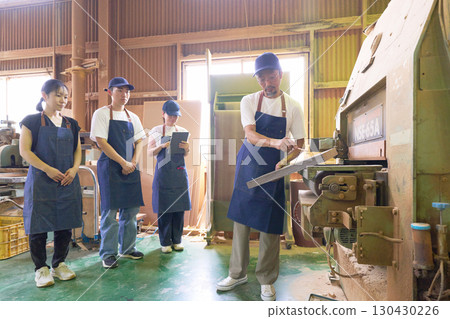 A scene from the workshop where a woodworker gives technical guidance to a young craftsman 130430226