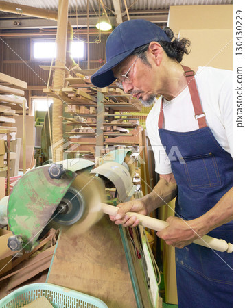 Skilled handiwork using a rotary grinder to process wood 130430229