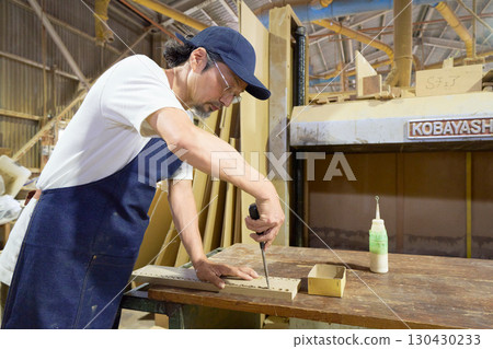 Woodworker finishing a hole in wood with a chisel 130430233