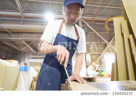 Woodworker finishing a hole in wood with a chisel 130430235