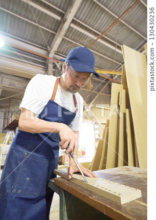 Woodworker finishing a hole in wood with a chisel 130430236