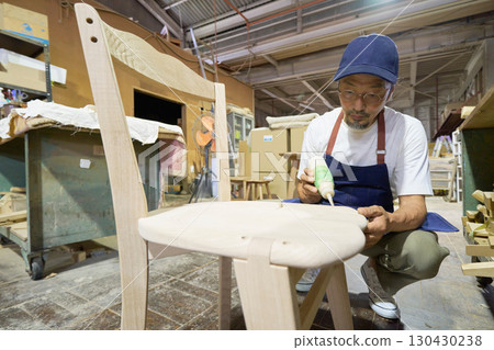 A craftsman gluing pieces together during the furniture assembly process 130430238