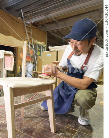 A woodworker finishing a chair with an electric sander A woodworker finishing a chair with an electric sander 130430244