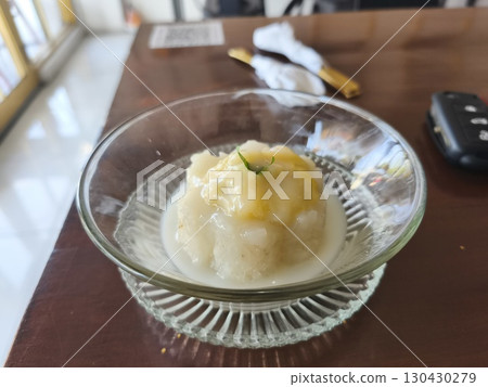 Traditional Thai dessert of sticky rice topped with durian and coconut milk, served in a glass bowl with a golden fork. 130430279