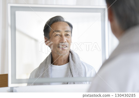 A man in his 60s smiling in the mirror. Men's beauty and health care image. A man in his 60s smiling in the mirror. Men's beauty and health care image. 130430285