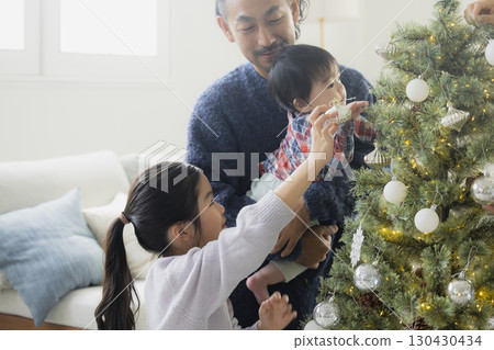 Families decorating Christmas trees 130430434