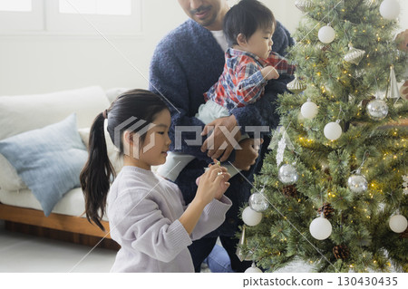 Families decorating Christmas trees 130430435