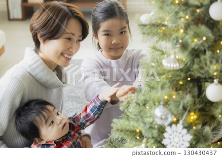 Families decorating Christmas trees Families decorating Christmas trees 130430437