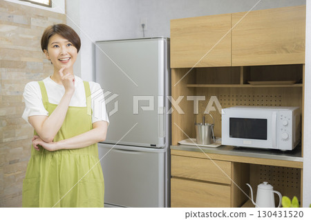 一名繫著圍裙的女子打開冰箱 130431520