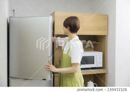 一名繫著圍裙的女子打開冰箱 一名繫著圍裙的女子打開冰箱 130431526