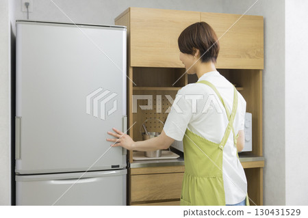 一名繫著圍裙的女子打開冰箱 一名繫著圍裙的女子打開冰箱 130431529