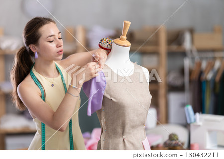 Woman seamstress adjusts clothes on mannequin 130432211