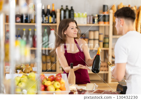 Female shop assistant helping customer select bottle of wine Female shop assistant helping customer select bottle of wine 130432230