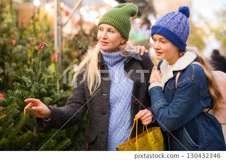 Mother and teenager daughter choosing Christmas tree at Christmas fair Mother and teenager daughter choosing Christmas tree at Christmas fair 130432346