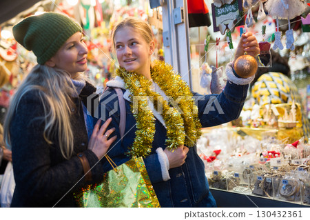Happy mother with daughter choosing Christmas decoration and balls at Christmas market Happy mother with daughter choosing Christmas decoration and balls at Christmas market 130432361