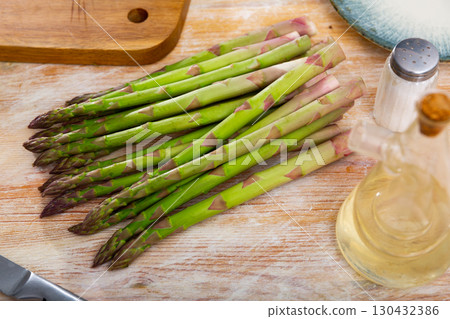 Fresh green asparagus spears on wooden table with knife 130432386