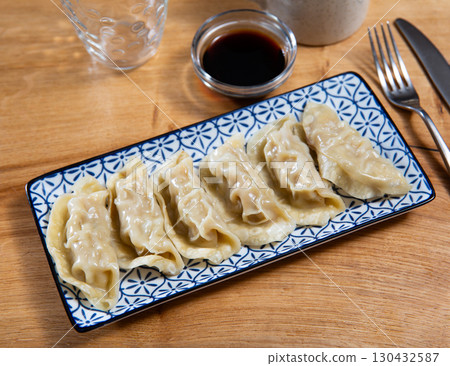 Boiled Yaki Gyoza served in plate with special sauce and chopsticks 130432587