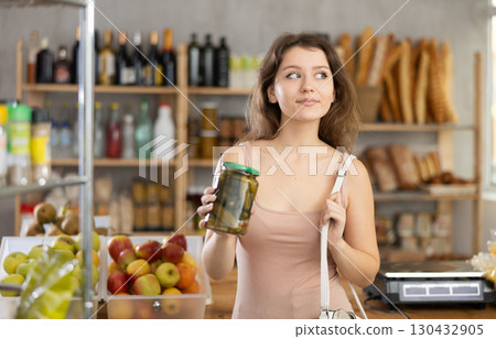 Female shopper selects canned goods in grocery supermarket Female shopper selects canned goods in grocery supermarket 130432905