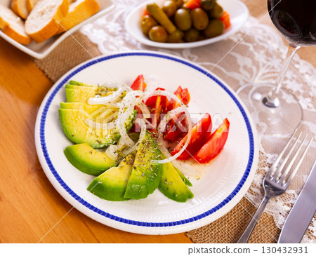 Olives, bread and glass of red wine are served with salad of red tomatoes, avocado and white onions Olives, bread and glass of red wine are served with salad of red tomatoes, avocado and white onions 130432931