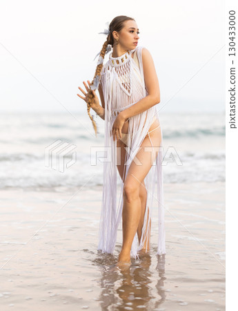 Barefoot girl on seashore in sexy and revealing Amazon tribe carnival costume. 130433000