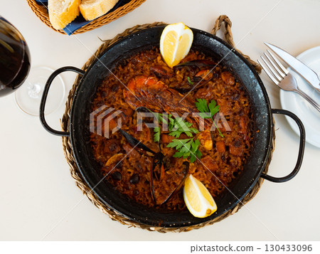 Traditional seafood paella with shrimps, squid and clams served in paellera Traditional seafood paella with shrimps, squid and clams served in paellera 130433096