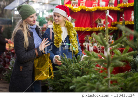 Happy mother and teenage daughter looking for Christmas tree on outdoor market 130433124