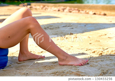 Women legs on seashore on summer day.Relax on beach sand 130433256