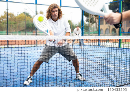 Caucasian man playing paddle tennis on padel court 130433293
