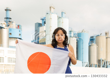 Sad young woman with flag of Japan against background of factory Sad young woman with flag of Japan against background of factory 130433332