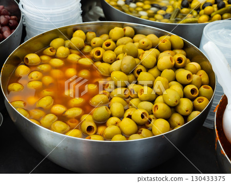 Green Spanish pitted olives in brine in container for sale 130433375