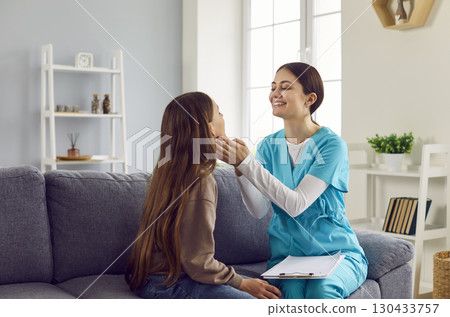 Woman pediatrician or otolaryngologist checks child's throat during her home visit Woman pediatrician or otolaryngologist checks child's throat during her home visit 130433757