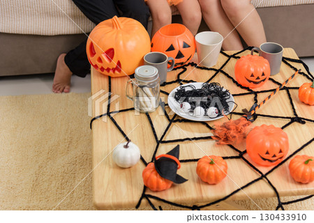 A table is decorated for a fun halloween day celebration, pumpkins and a spider web decorate the table for parties for children and adults at home. 130433910