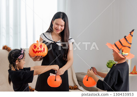 Happy woman with pumpkin and two children with their baskets are ready for trick or treat, wearing festive hats and preparing for halloween day fun at home. Happy woman with pumpkin and two children with their baskets are ready for trick or treat, wearing festive hats and preparing for halloween day fun at home. 130433953