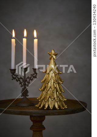 Christmas tree and candle stand on an antique side table 130434240
