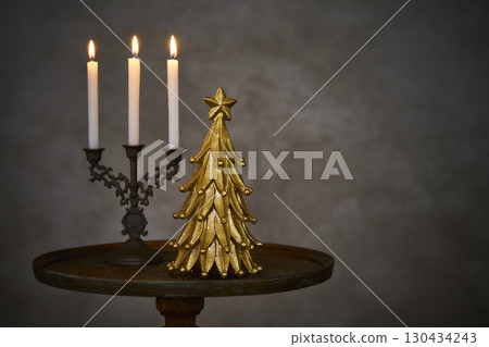 Christmas tree and candle stand on an antique side table 130434243