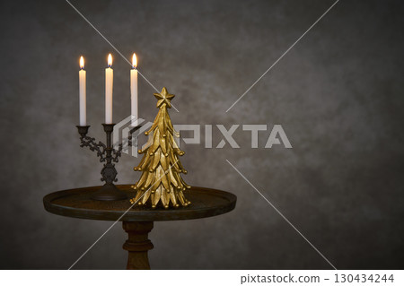 Christmas tree and candle stand on an antique side table 130434244