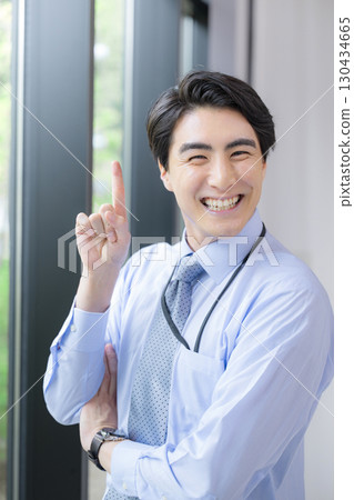 一位身穿領帶和襯衫的年輕人在商務環境中微笑著,用指點的表情看著鏡頭 一位身穿領帶和襯衫的年輕人在商務環境中微笑著,用指點的表情看著鏡頭 130434665