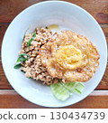 Spicy Thai Basil Pork with a Crispy Fried Egg on a White Plate 130434739