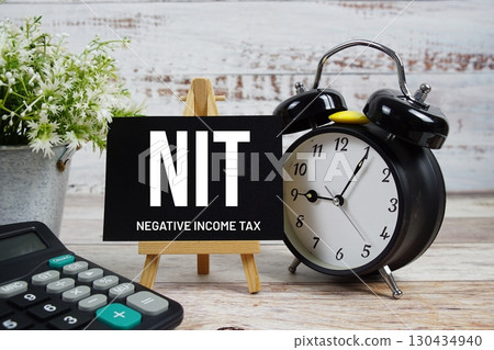 NIT Negative Income Tax text with alarm clock and calculator on wooden background 130434940