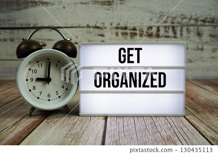 Get Organized text on light box with alarm clock on wooden background 130435113