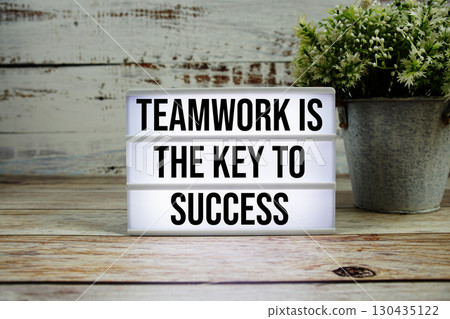 Teamwork is the Key to Success text on light box with alarm clock on wooden background 130435122