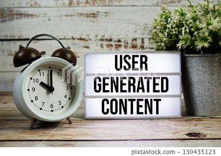 User Generated Content text on light box with alarm clock on wooden background 130435123