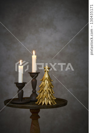 Christmas tree and candle stand on an antique side table 130435171