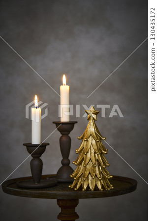 Christmas tree and candle stand on an antique side table 130435172