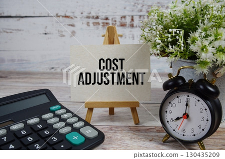 Cost Adjustment text with alarm clock and calculator on wooden background 130435209